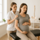 A pregnant woman receives gentle chiropractic support from a practitioner in a calm, sunlit clinic.